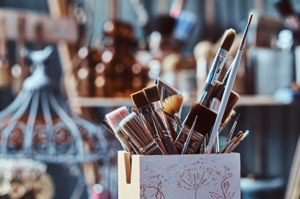 Jar with different brushes on the table at art studio